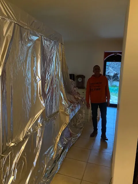 Grande enveloppe étanche en film aluminium fermée le long d’un couloir, à côté d’un technicien