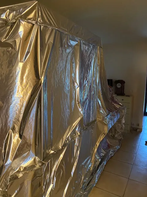 Longue enveloppe étanche en film aluminium le long d’un mur, avec une horloge et une commode au fond