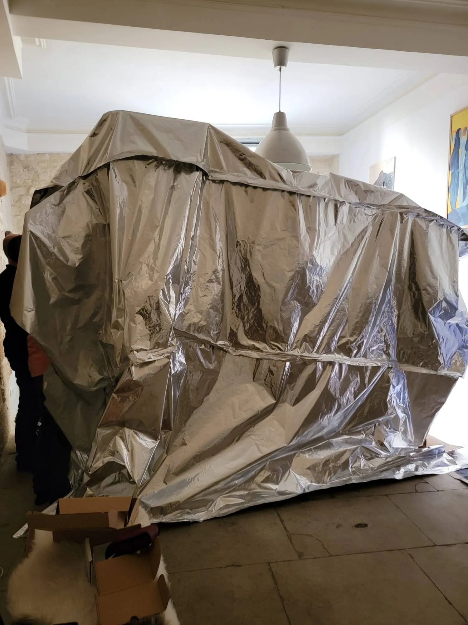 Grande enveloppe étanche en film aluminium fermée autour de l’ensemble du mobilier, au milieu d’une pièce