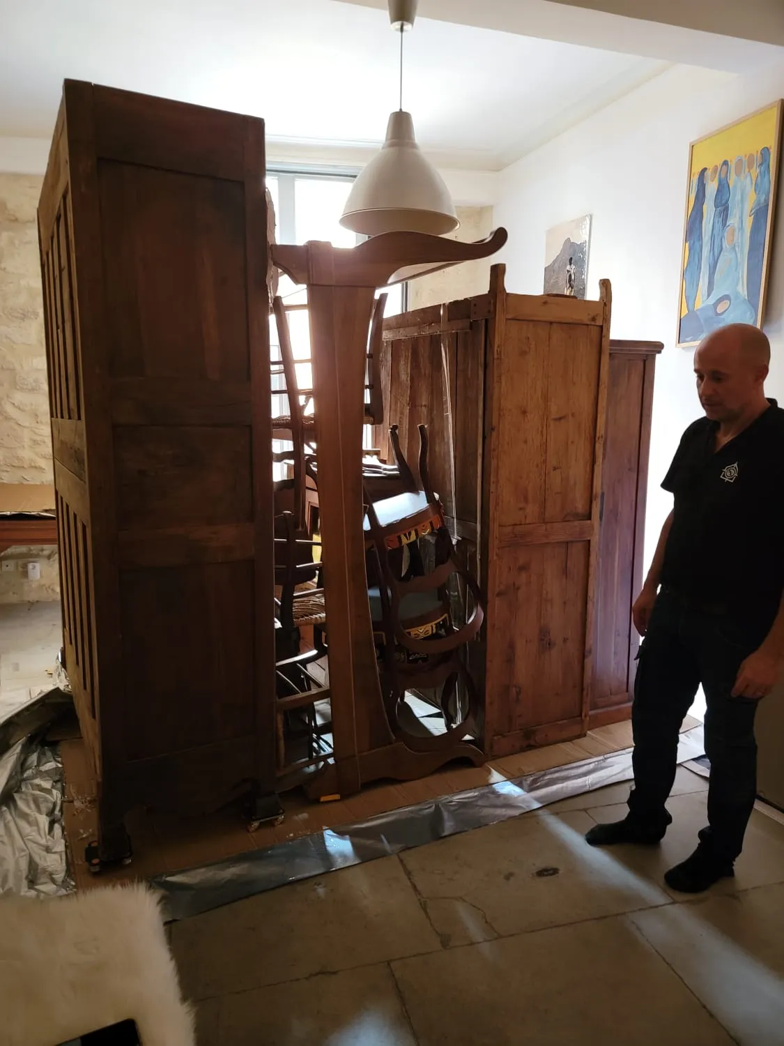 Pascal Sergent à côté du mobilier ancien regroupé sur cartons et film barrière, avant la pose de l’enveloppe